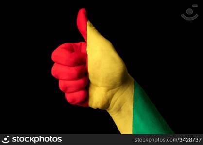 Hand with thumb up gesture in colored guinea national flag as symbol of excellence, achievement, good, - for tourism and touristic advertising, positive political, cultural, social management of country