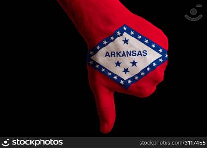 Hand with thumbs down gesture in colored american state of arkansas flag as symbol of negative political, cultural, social management of state