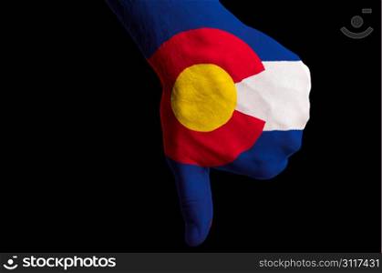 Hand with thumbs down gesture in colored american state of colorado flag as symbol of negative political, cultural, social management of state