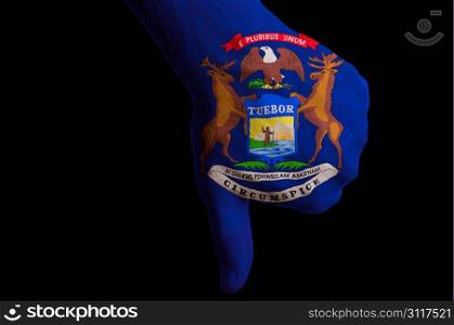 Hand with thumbs down gesture in colored american state of michigan flag as symbol of negative political, cultural, social management of state