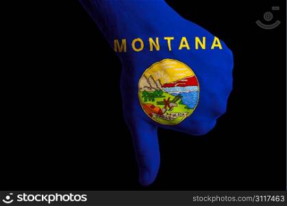 Hand with thumbs down gesture in colored american state of montana flag as symbol of negative political, cultural, social management of state
