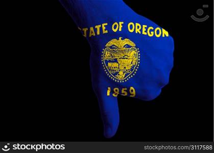 Hand with thumbs down gesture in colored american state of oregon flag as symbol of negative political, cultural, social management of state