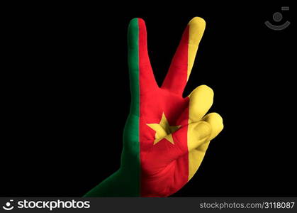 Hand with two finger up gesture in colored cameroon national flag as symbol of winning, victorious, excellent, - for tourism and touristic advertising, positive political, cultural, social management of country