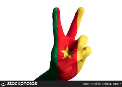 Hand with two finger up gesture in colored cameroon national flag as symbol of winning, victorious, excellent, - for tourism and touristic advertising, positive political, cultural, social management of country