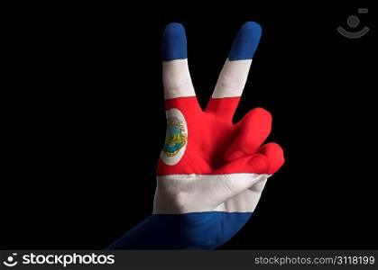 Hand with two finger up gesture in colored costa rica national flag as symbol of winning, victorious, excellent, - for tourism and touristic advertising, positive political, cultural, social management of country