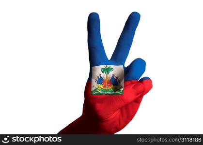 Hand with two finger up gesture in colored haiti national flag as symbol of winning, victorious, excellent, - for tourism and touristic advertising, positive political, cultural, social management of country