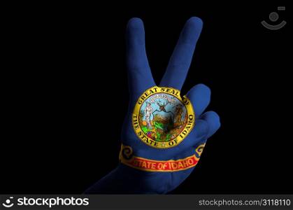 Hand with two finger up gesture in colored idaho state flag as symbol of winning, victorious, excellent, - for tourism and touristic advertising, positive political, cultural, social management of country