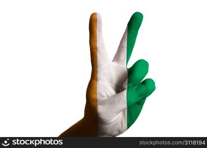 Hand with two finger up gesture in colored ivory coast national flag as symbol of winning, victorious, excellent, - for tourism and touristic advertising, positive political, cultural, social management of country