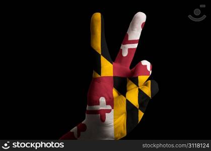 Hand with two finger up gesture in colored maryland state flag as symbol of winning, victorious, excellent, - for tourism and touristic advertising, positive political, cultural, social management of country