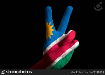 Hand with two finger up gesture in colored namibia national flag as symbol of winning, victorious, excellent, - for tourism and touristic advertising, positive political, cultural, social management of country