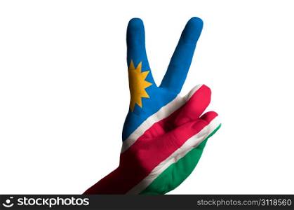 Hand with two finger up gesture in colored namibia national flag as symbol of winning, victorious, excellent, - for tourism and touristic advertising, positive political, cultural, social management of country