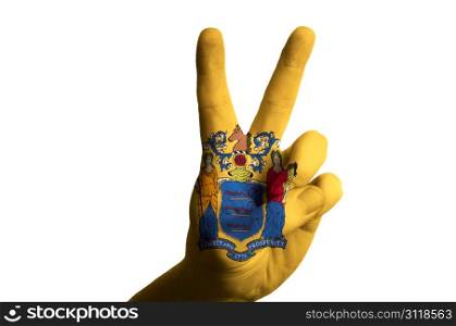 Hand with two finger up gesture in colored new jersey state flag as symbol of winning, victorious, excellent, - for tourism and touristic advertising, positive political, cultural, social management of country