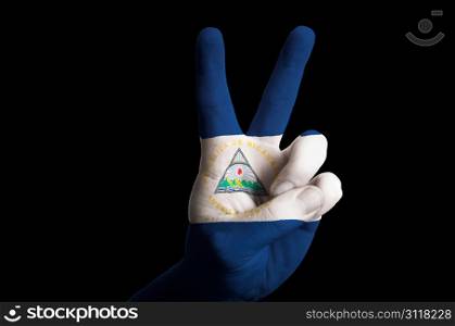 Hand with two finger up gesture in colored nicaragua national flag as symbol of winning, victorious, excellent, - for tourism and touristic advertising, positive political, cultural, social management of country