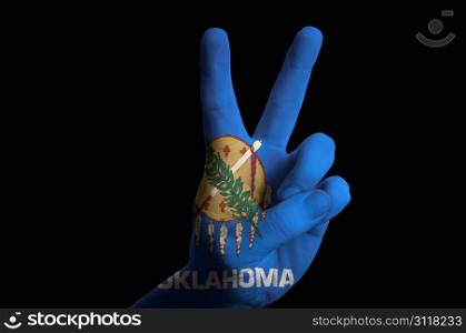 Hand with two finger up gesture in colored oregon oklahoma state flag as symbol of winning, victorious, excellent, - for tourism and touristic advertising, positive political, cultural, social management of country
