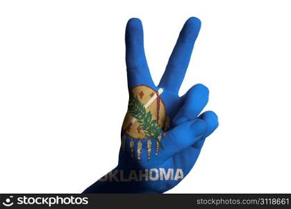 Hand with two finger up gesture in colored oregon oklahoma state flag as symbol of winning, victorious, excellent, - for tourism and touristic advertising, positive political, cultural, social management of country