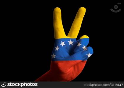 Hand with two finger up gesture in colored venezuela national flag as symbol of winning, victorious, excellent, - for tourism and touristic advertising, positive political, cultural, social management of country