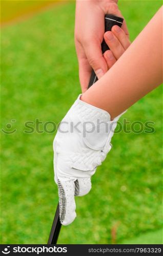 hand with white gloves holding golf a putter