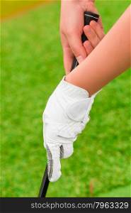 hand with white gloves holding golf a putter
