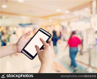 Hand woman holding and using phone with blurred background in shopping mall.