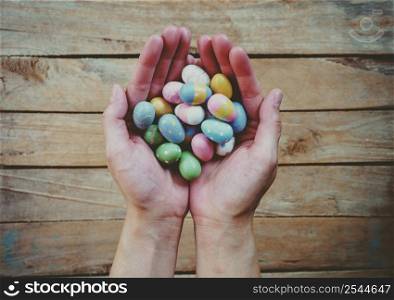 Hand woman holding colorful easter eggs on wood table background.