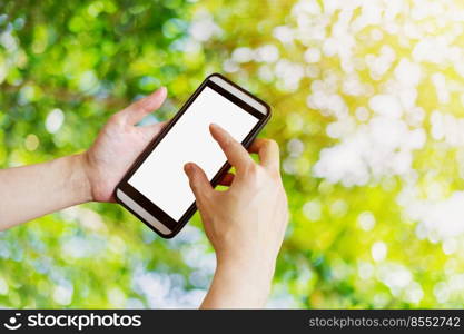 Hand woman using phone in garden with bokeh and sunlight.