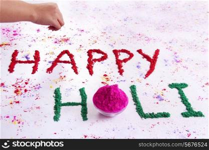 Hand writing HAPPY Holi with gulal over white background