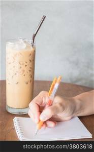 Hand writing on note paper in coffee shop, stock photo
