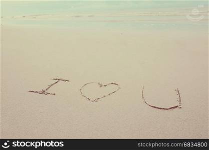 Hand written i love you on sand beach with copy space, vintage style tone