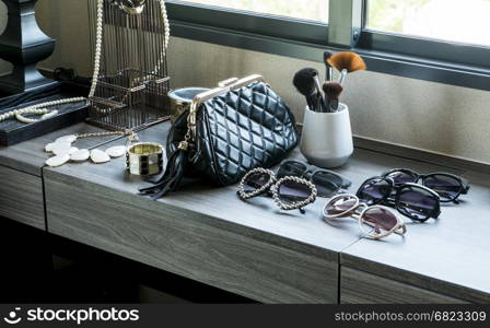 handbag,sunglasses, jewelry and makeup brushes on a black table