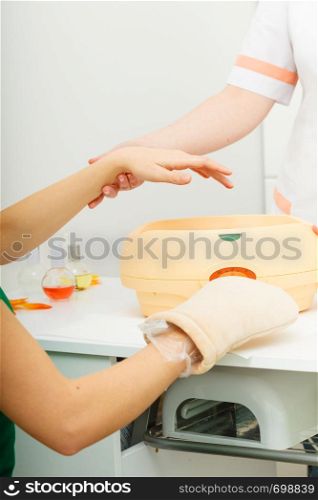 Handcare, beauty studio wellness treatments concept. Woman getting paraffin hand treatment at spa salon.. Woman getting paraffin hand treatment at beautician