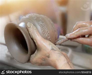 Handcraft artist making pattern with stick on earthenware pottery in workshop studio.