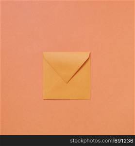 Handcraft envelope mockup for congratulation post card on a light peach color background with copy space. Flat lay.. Empty handmade mock up envelope on a peach color background .