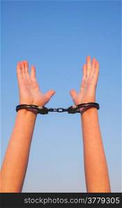 Handcuffed woman hands against blue sky