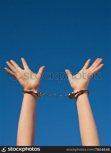 Handcuffed woman&rsquo;s hands against blue sky