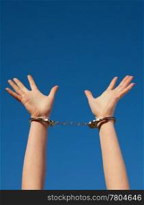 Handcuffed woman&rsquo;s hands against blue sky