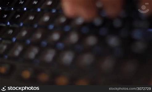Hande eines Mannes geben Daten in ein modernes beleuchtetes Keyboard ein