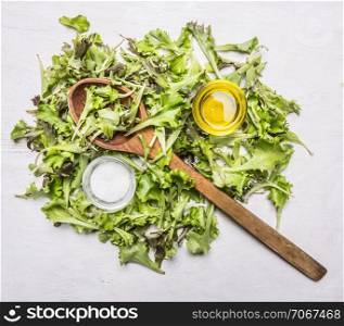 handful fresh salad Lollo rosso with a wooden spoon, oil and salt on wooden rustic background top view close up