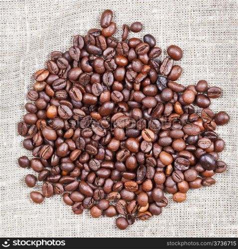 handful of roasted coffee beans on sackcloth close up