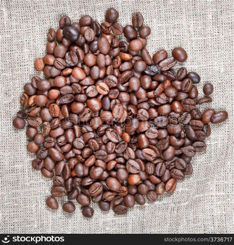 handful of roasted coffee beans on textile close up