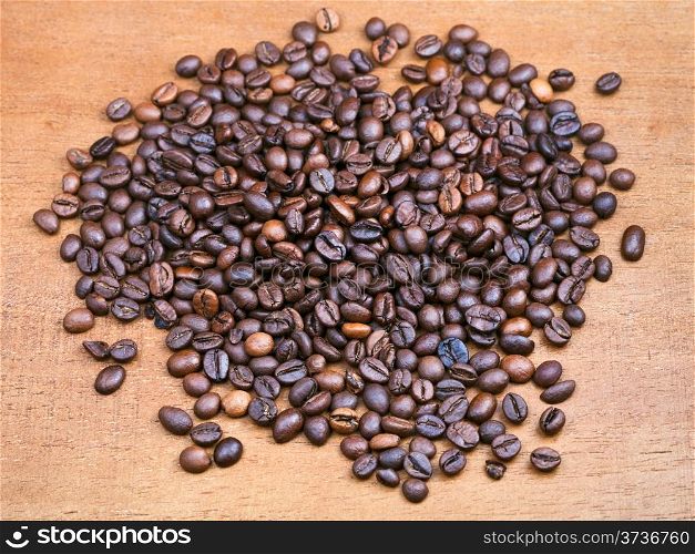 handful of roasted coffee beans on wooden board close up