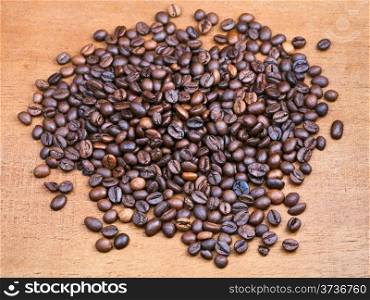 handful of roasted coffee beans on wooden board close up