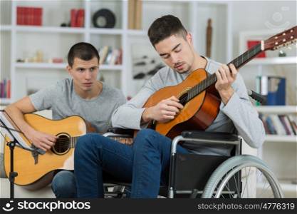 handicapped teenager playing the guitar with his friend