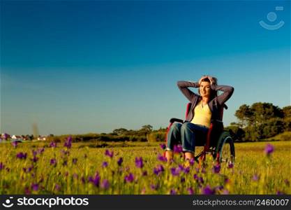 Handicapped woman on a wheelchair over a green meadow