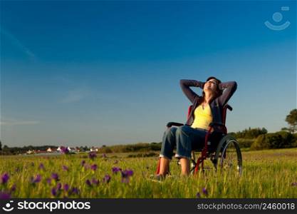Handicapped woman on a wheelchair over a green meadow