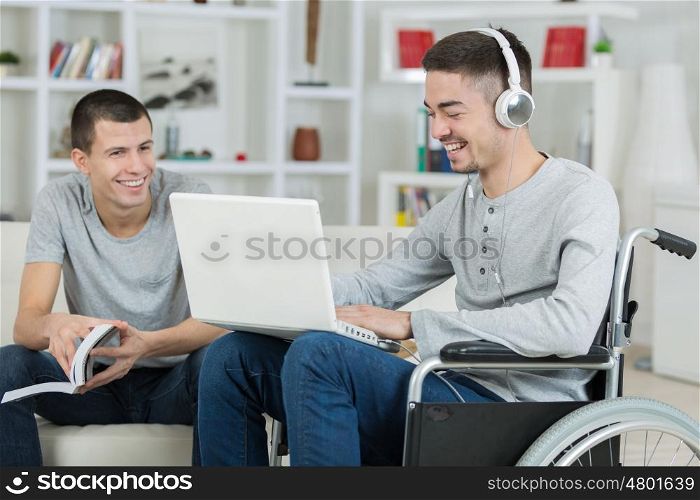 handicapped young man and friend checking music on a laptop