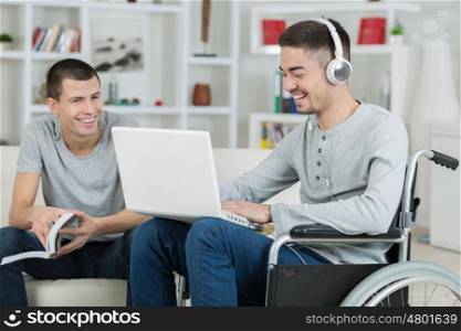 handicapped young man and friend checking music on a laptop
