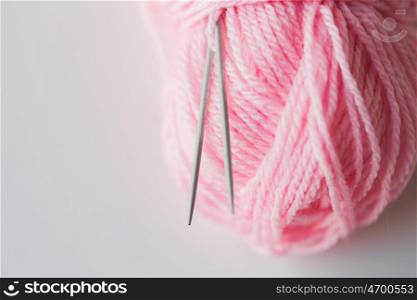 handicraft and needlework concept - close up of knitting needles and ball of pink yarn on white. close up of knitting needles and pink yarn ball