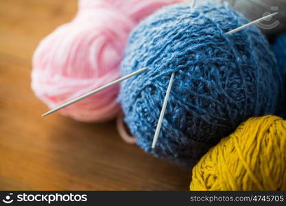 handicraft and needlework concept - close up of knitting needles and balls of yarn on wood. close up of knitting needles and yarn balls