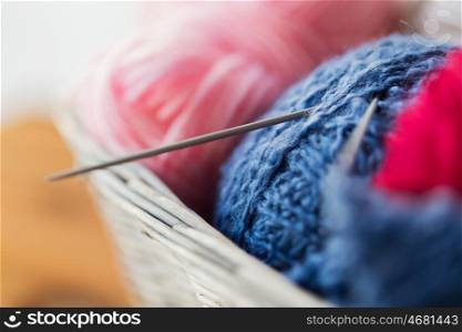 handicraft and needlework concept - close up of wicker basket with knitting needles and balls of yarn. basket with knitting needles and balls of yarn