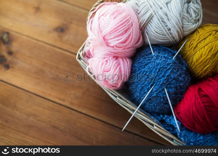 handicraft and needlework concept - close up of wicker basket with knitting needles and balls of yarn. basket with knitting needles and balls of yarn